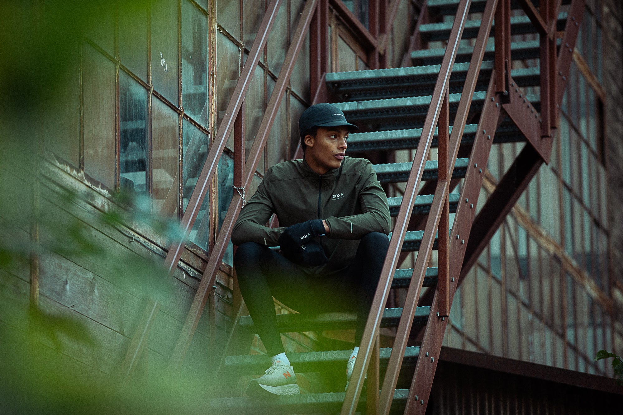 Person sitting on metal stairs in an urban setting wearing running apparel from DOXA RUN